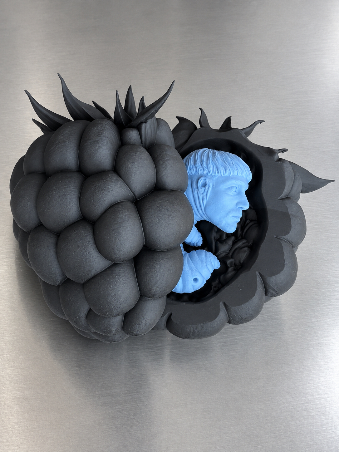 Black raspberry sculpture opening to reveal a blue larval self-portrait