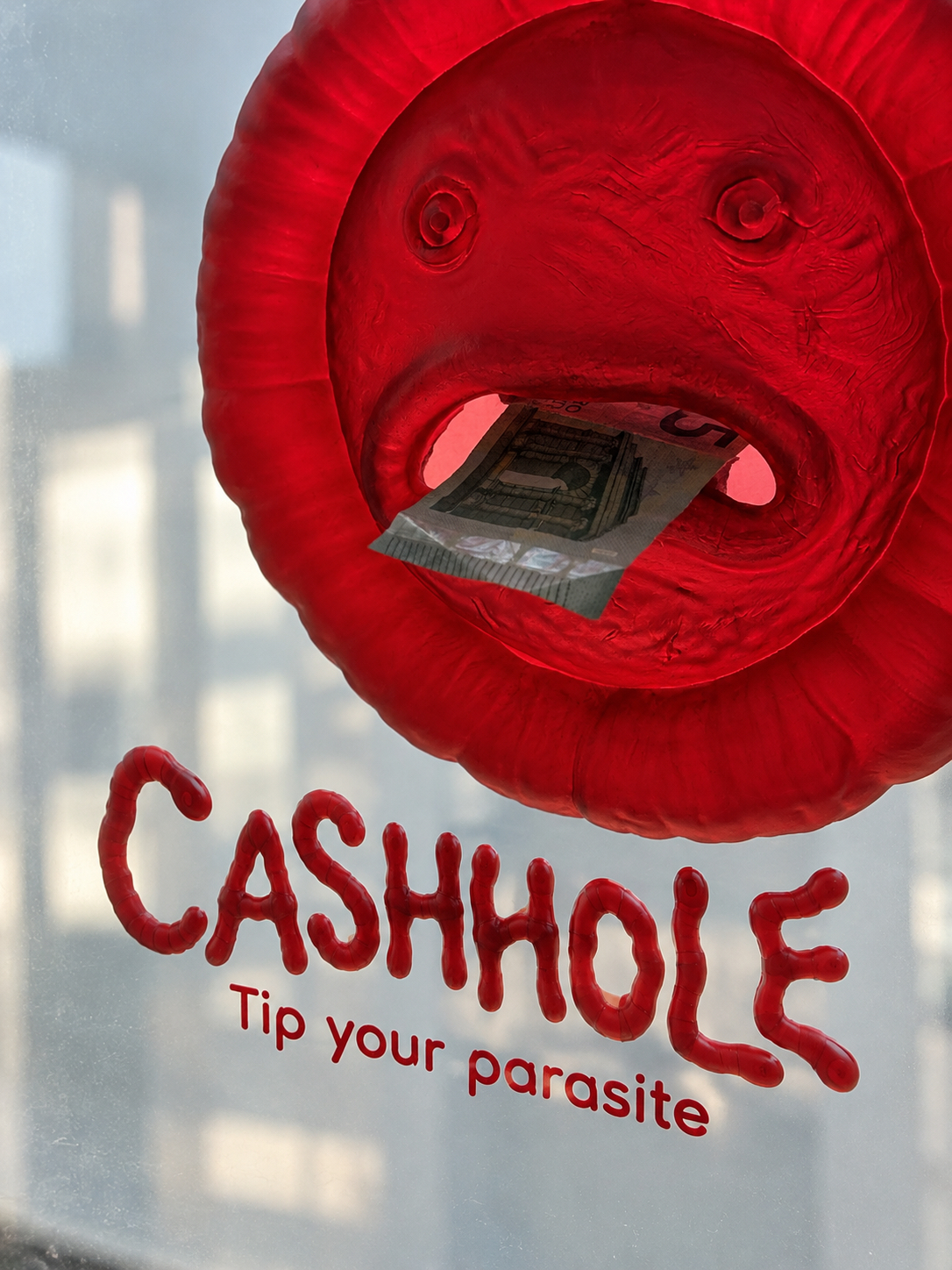 Cashhole red resin money box installed with a banknote in its mouth