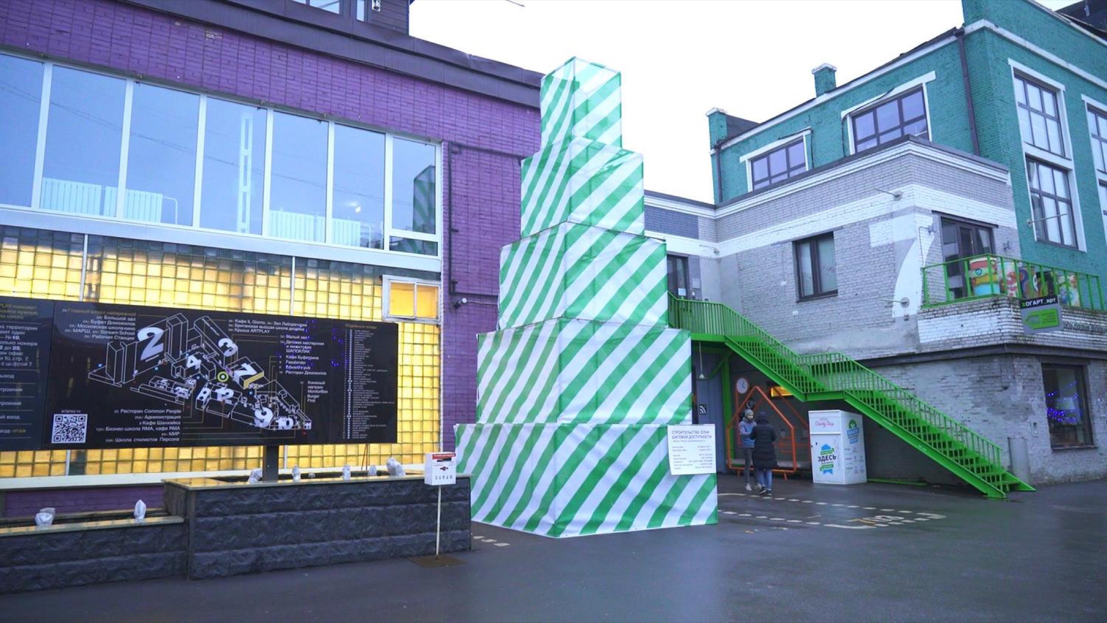 Wide exterior view of Christmas Tree Under Construction installed in an urban courtyard