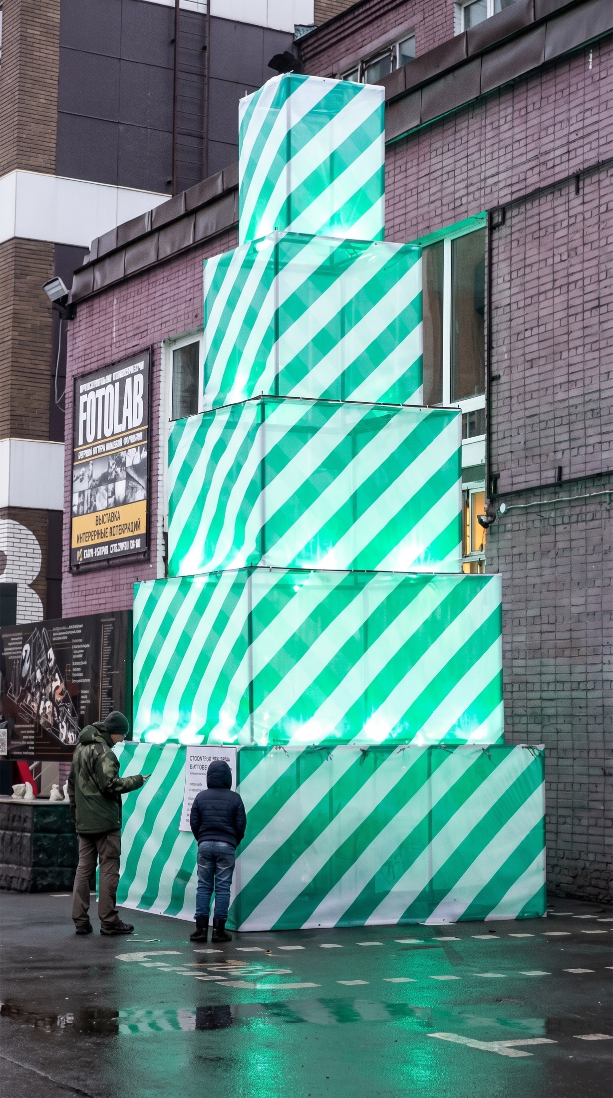 Christmas Tree Under Construction sculpture glowing green with two visitors standing nearby