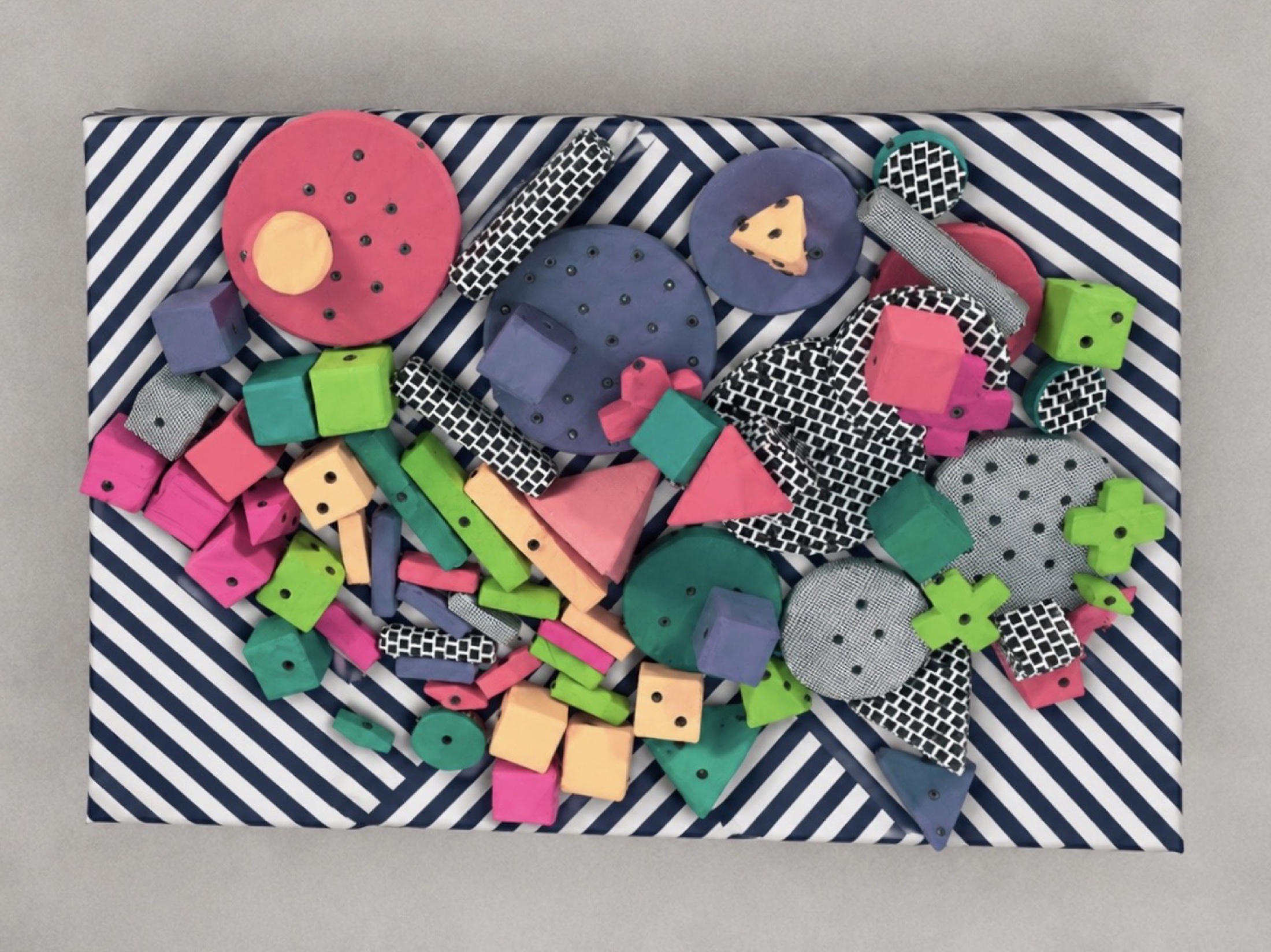 Horizontal view of Human Kit soft snap-fastened components arranged on a striped surface