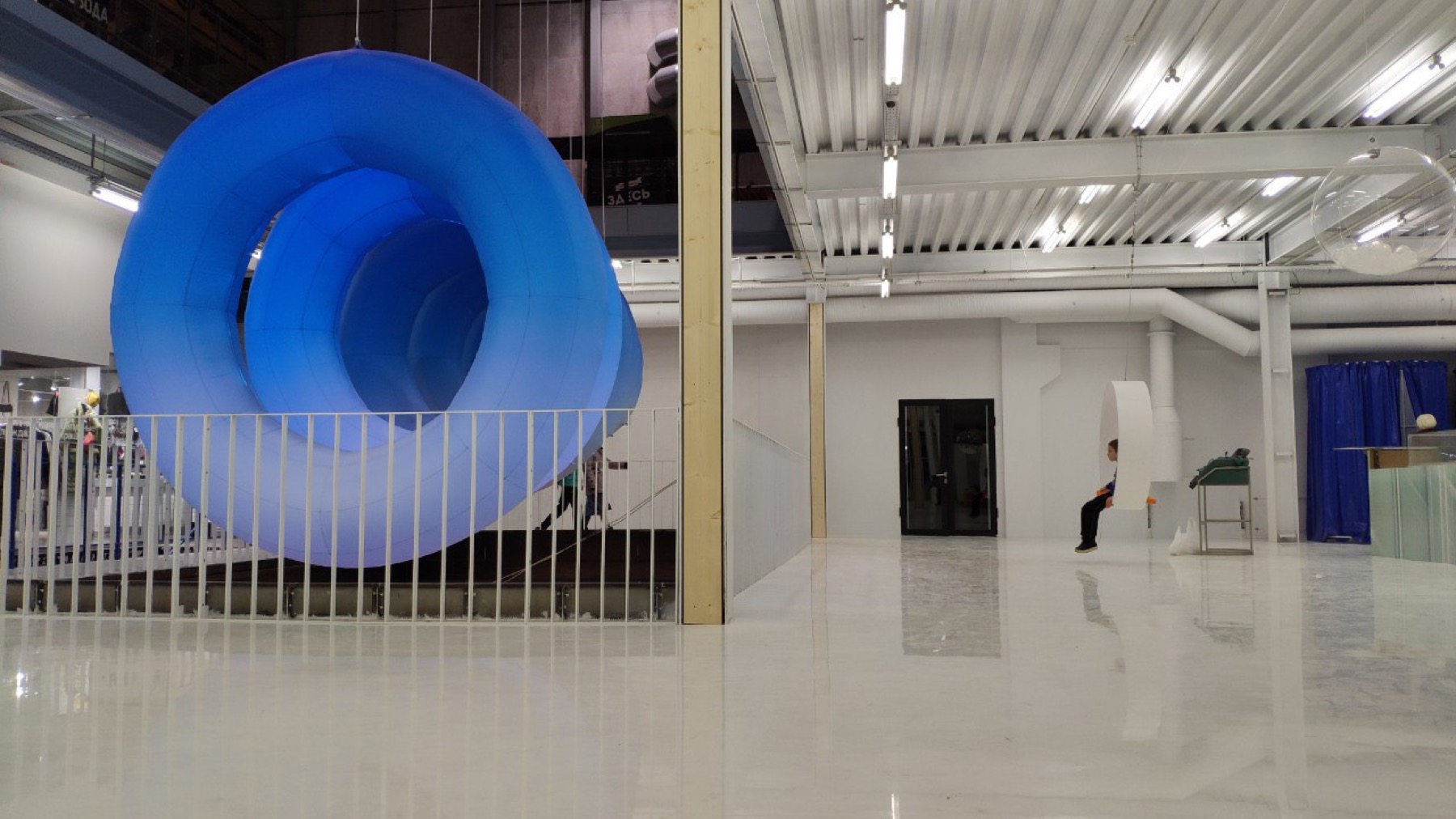 Side view of the blue inflatable 1=0 structure in a white exhibition space
