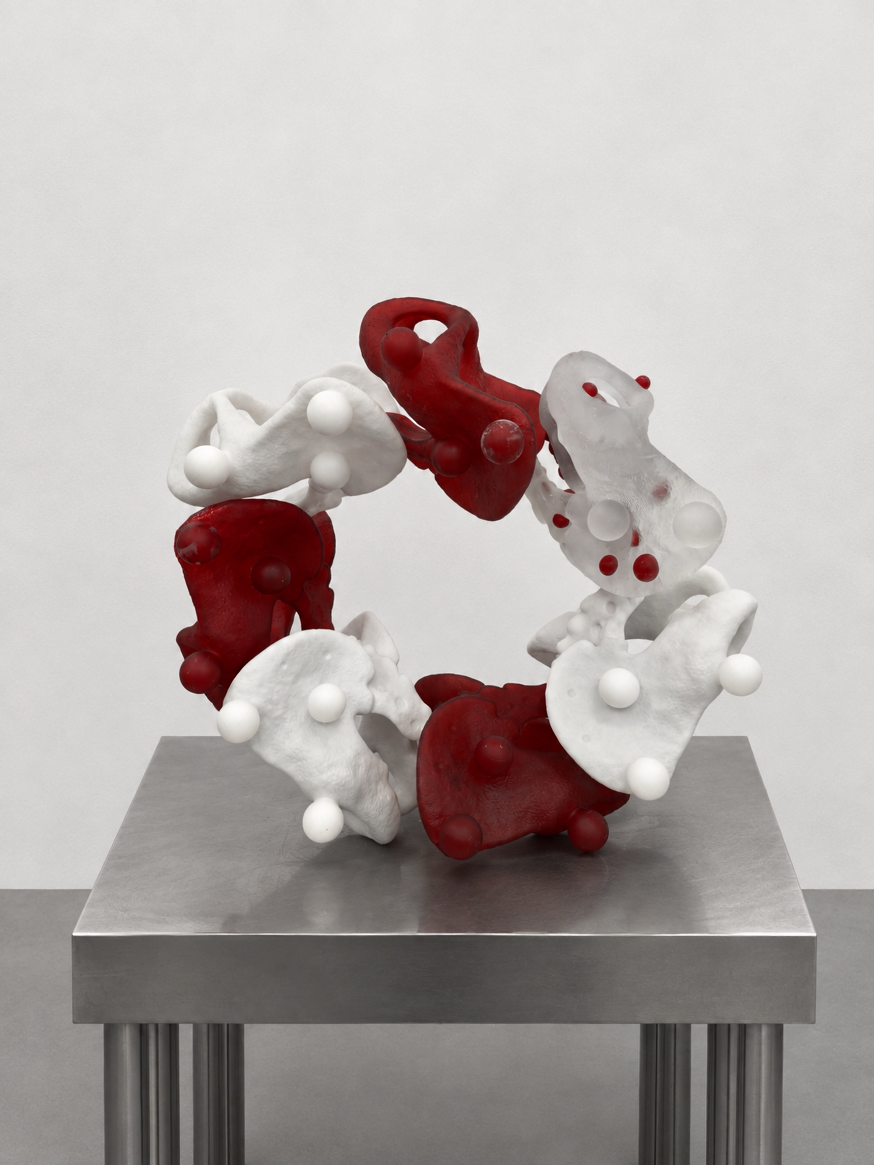Circular red, white, and translucent Rebone organizm'os assembly on a metal plinth