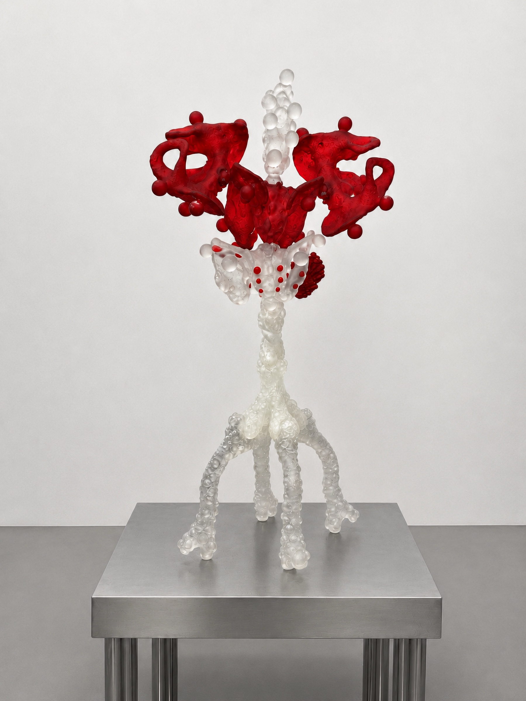 Tall translucent and red Rebone organizm'os organism on a metal plinth