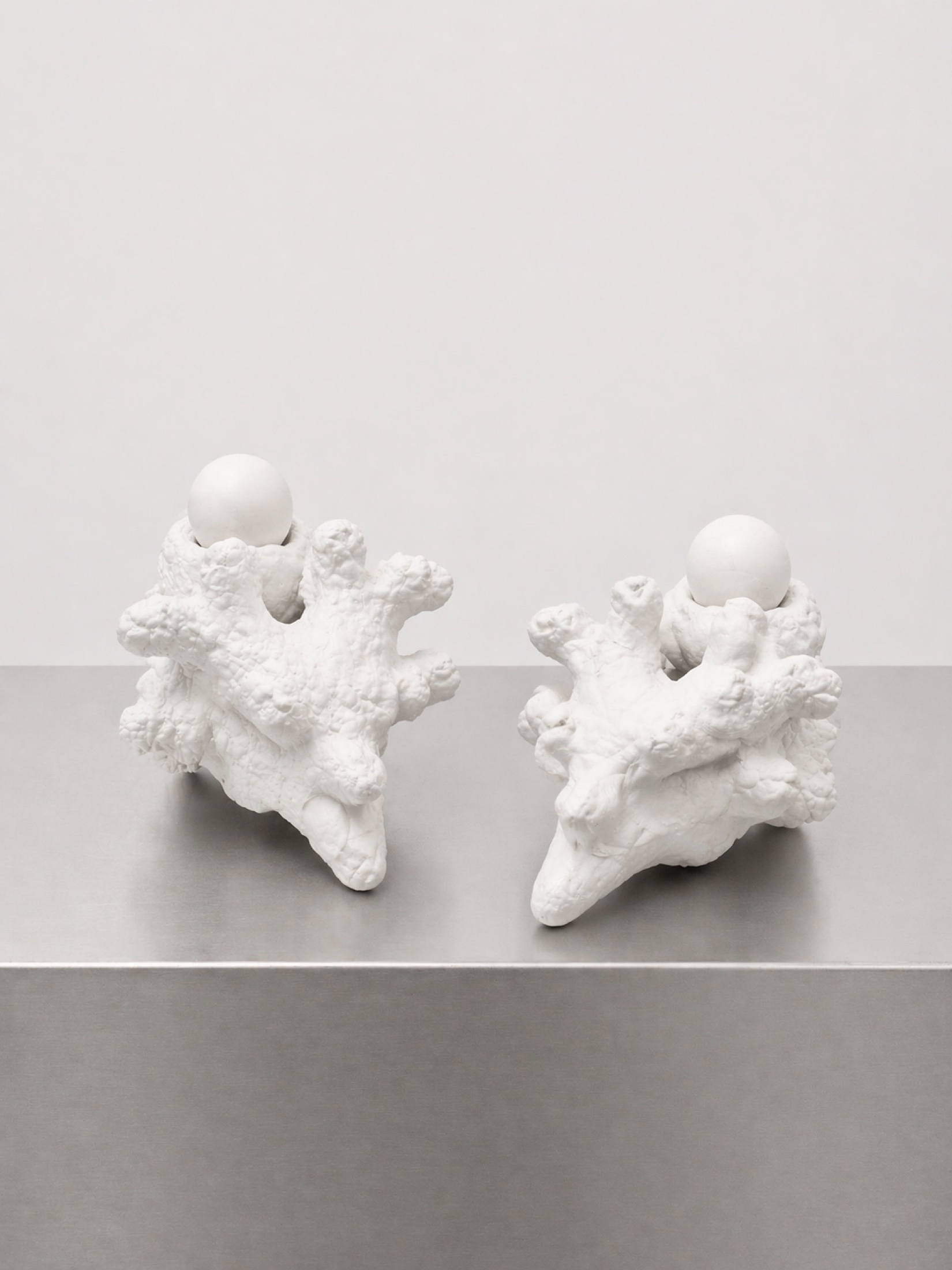 Two white Rebone organizm’os bone-like elements on a metal plinth