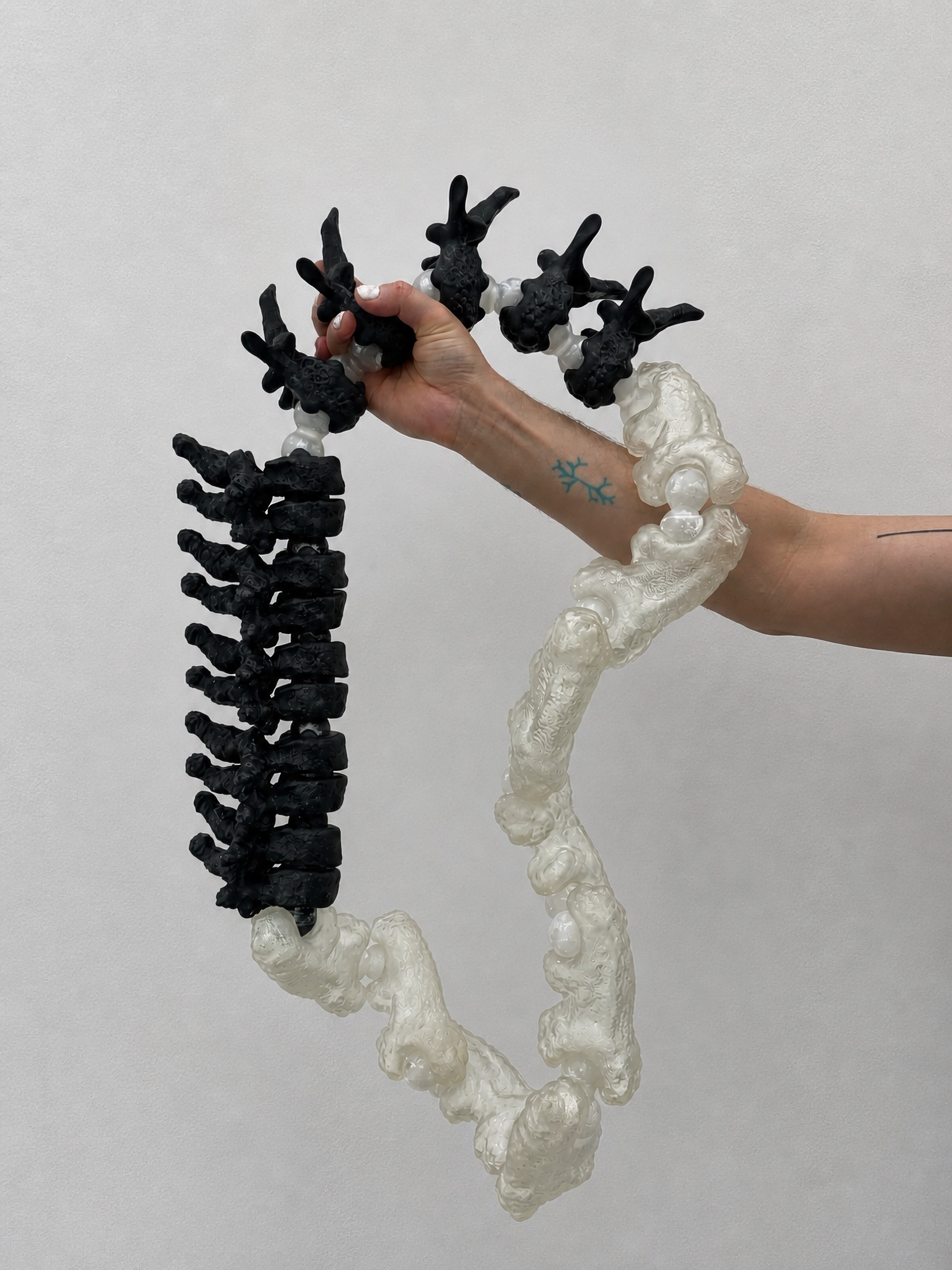 Hand holding a black and translucent Rebone organizm'os spine-like structure