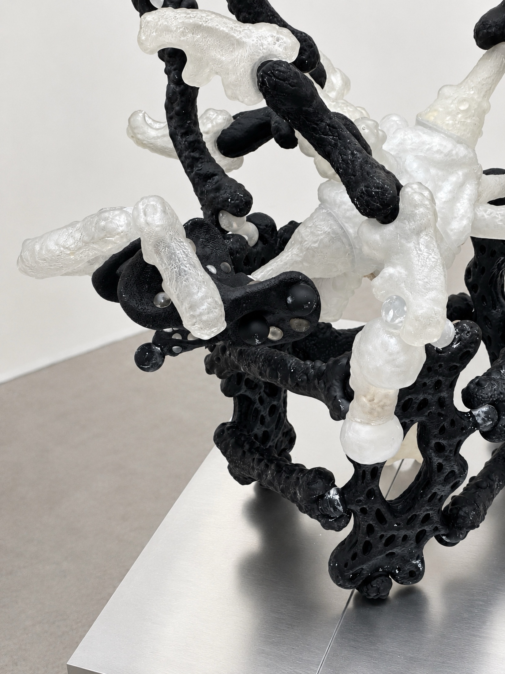 Close view of black and translucent Rebone organizm'os elements interlocked on a metal plinth