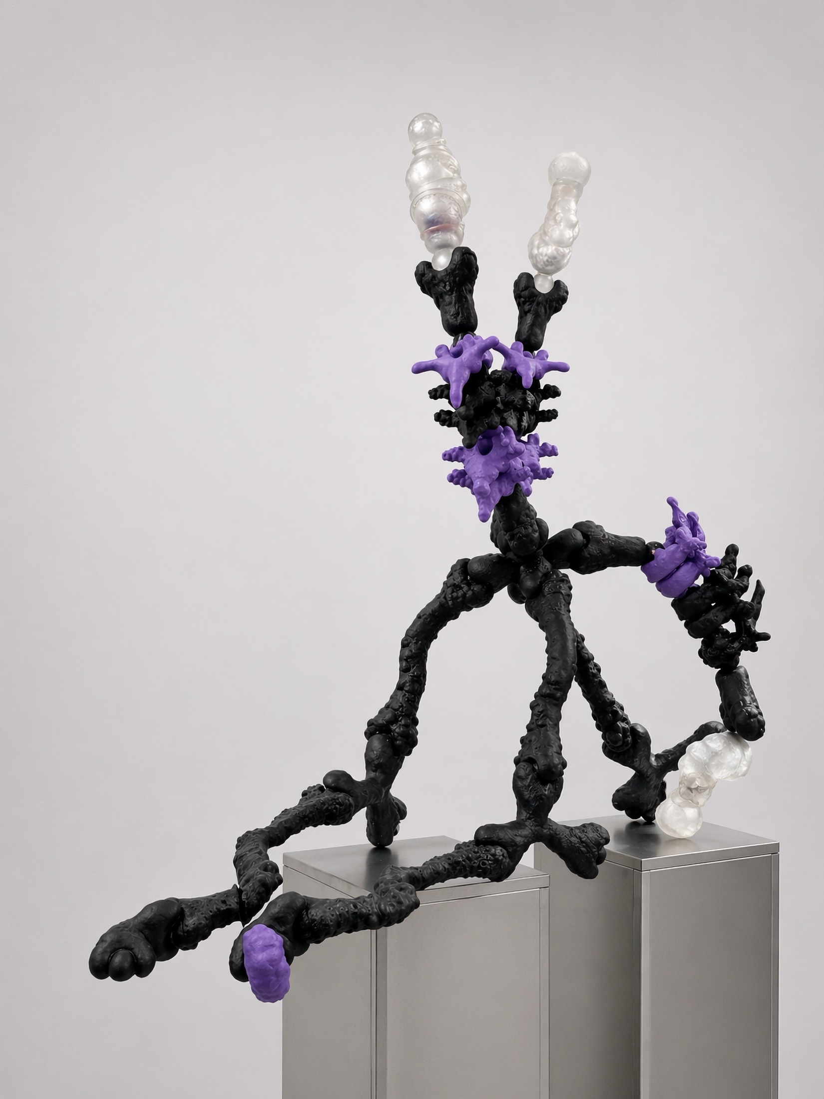 Black and purple Rebone organizm'os organism stretched between metal plinths