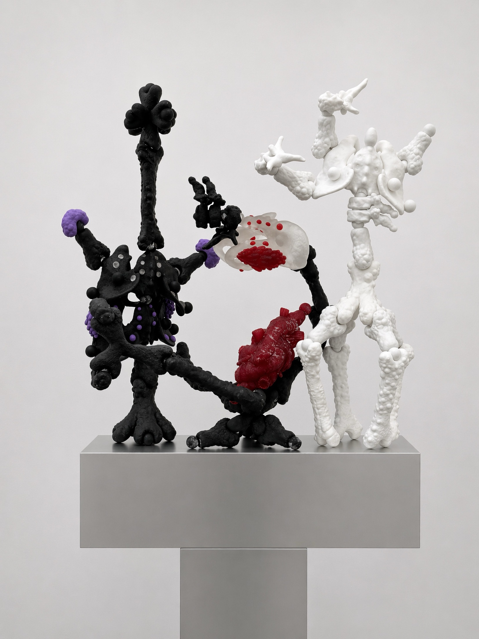 Black, white, and red Rebone organizm’os assemblage standing on a metal plinth