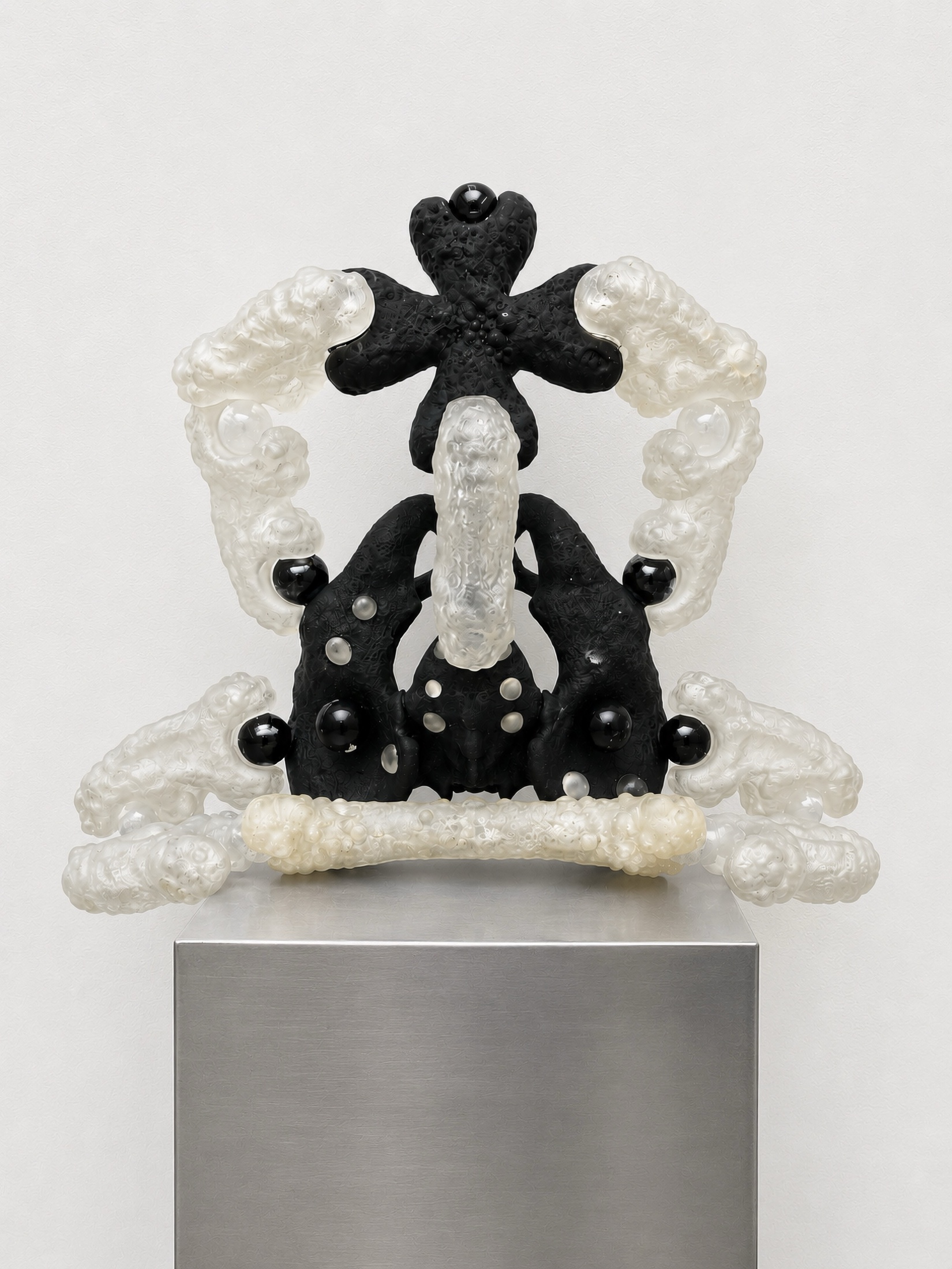 Black and translucent Rebone organizm’os symmetrical object on a metal plinth