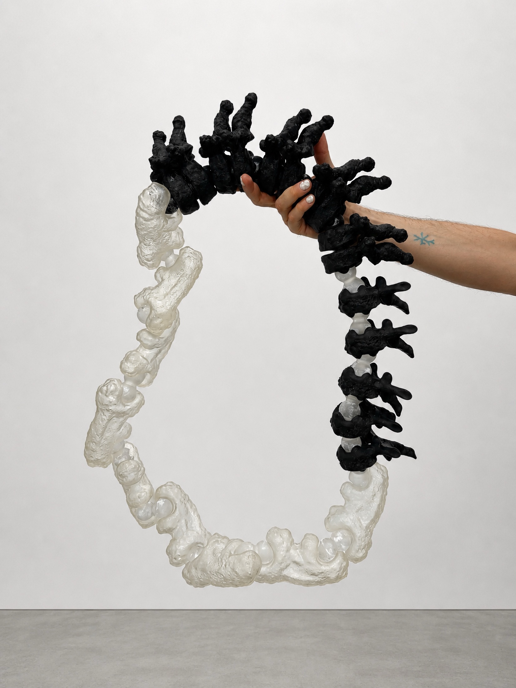 Hand holding a black and translucent Rebone organizm’os ring-like structure