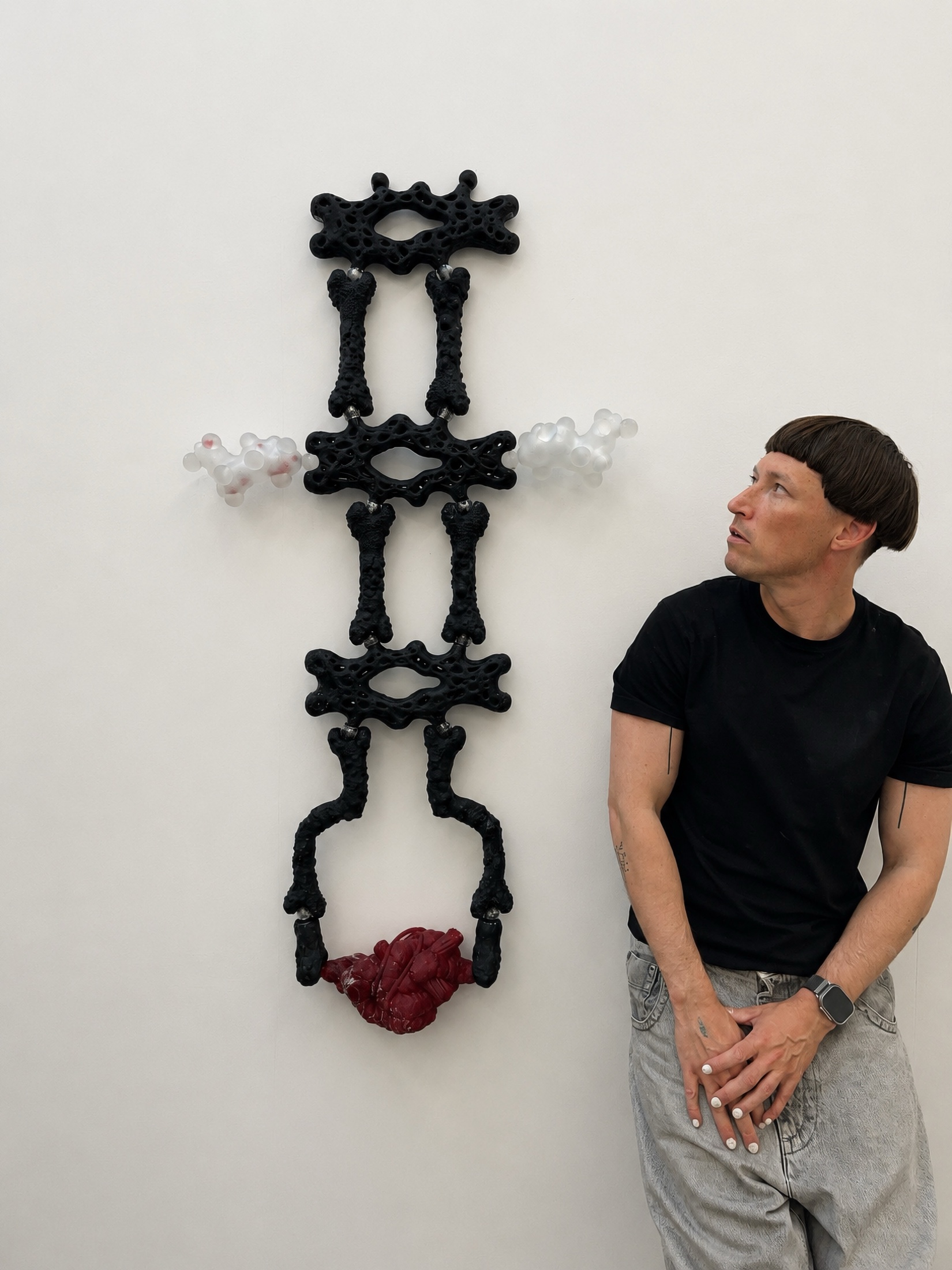 Ottone Radavi beside a black Rebone organizm'os wall structure with a red organ element