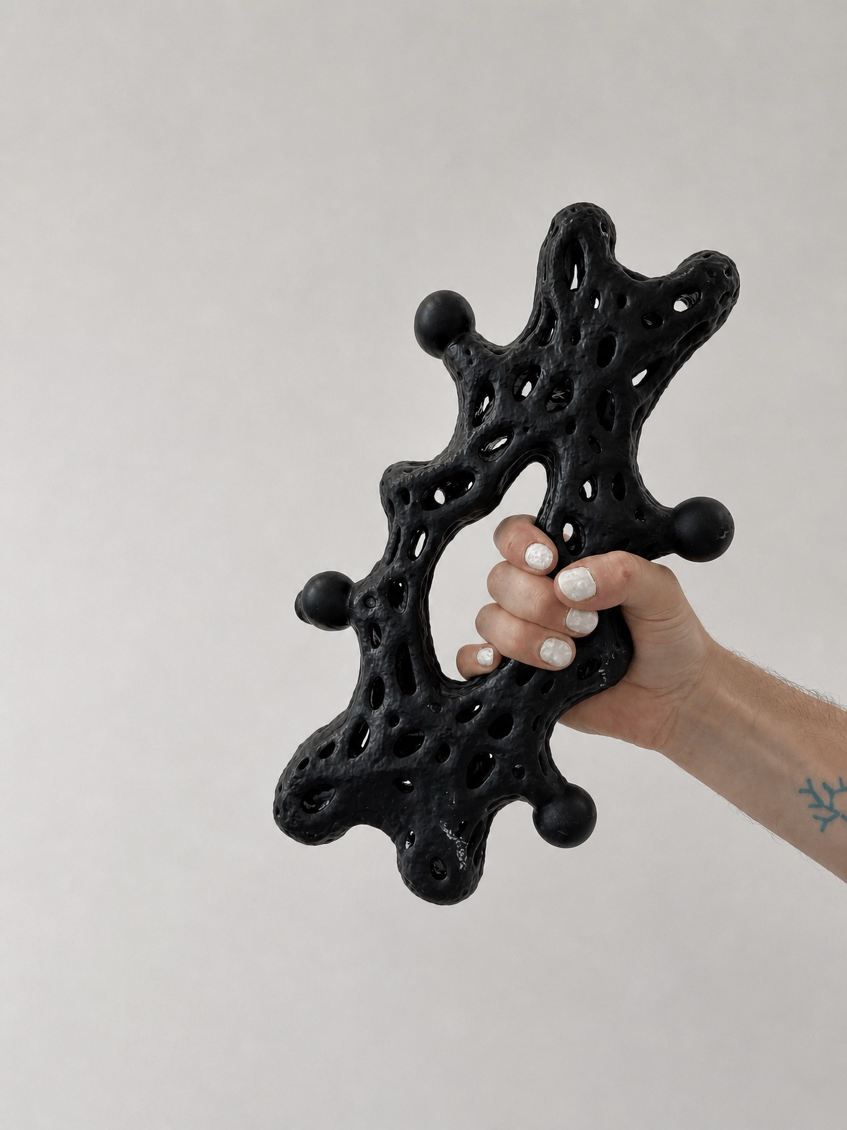 Hand holding a black perforated Rebone organizm'os component