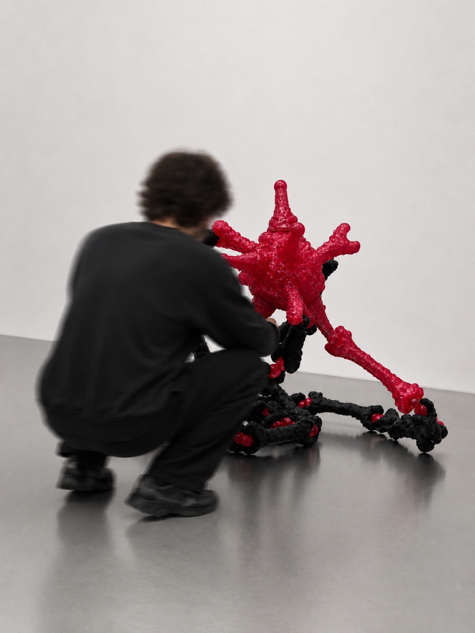 Visitor crouching beside a black and red Rebone organizm'os temporary organism