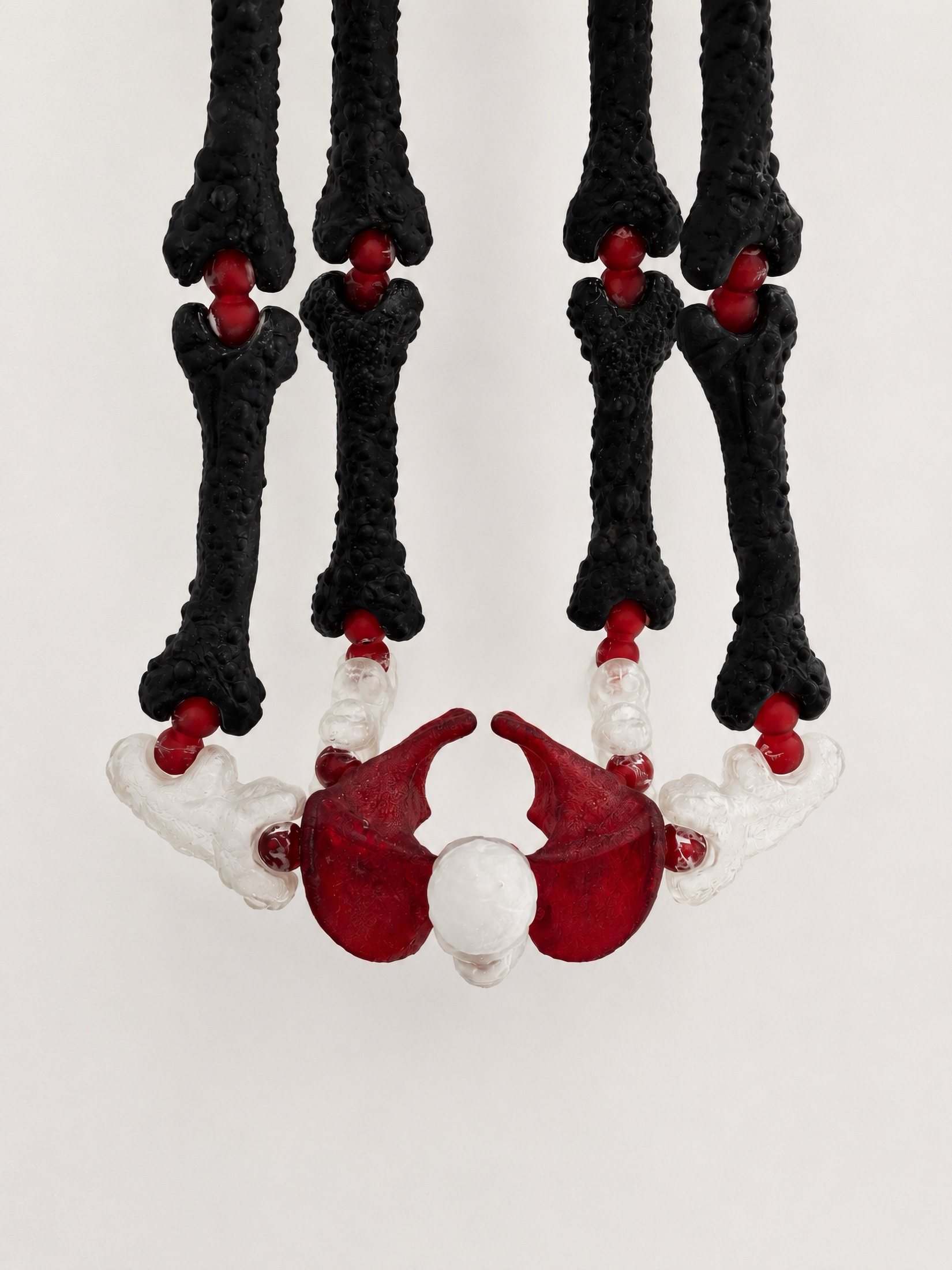 Close view of black bone-like Rebone organizm'os elements with red spherical joints and a translucent pelvis