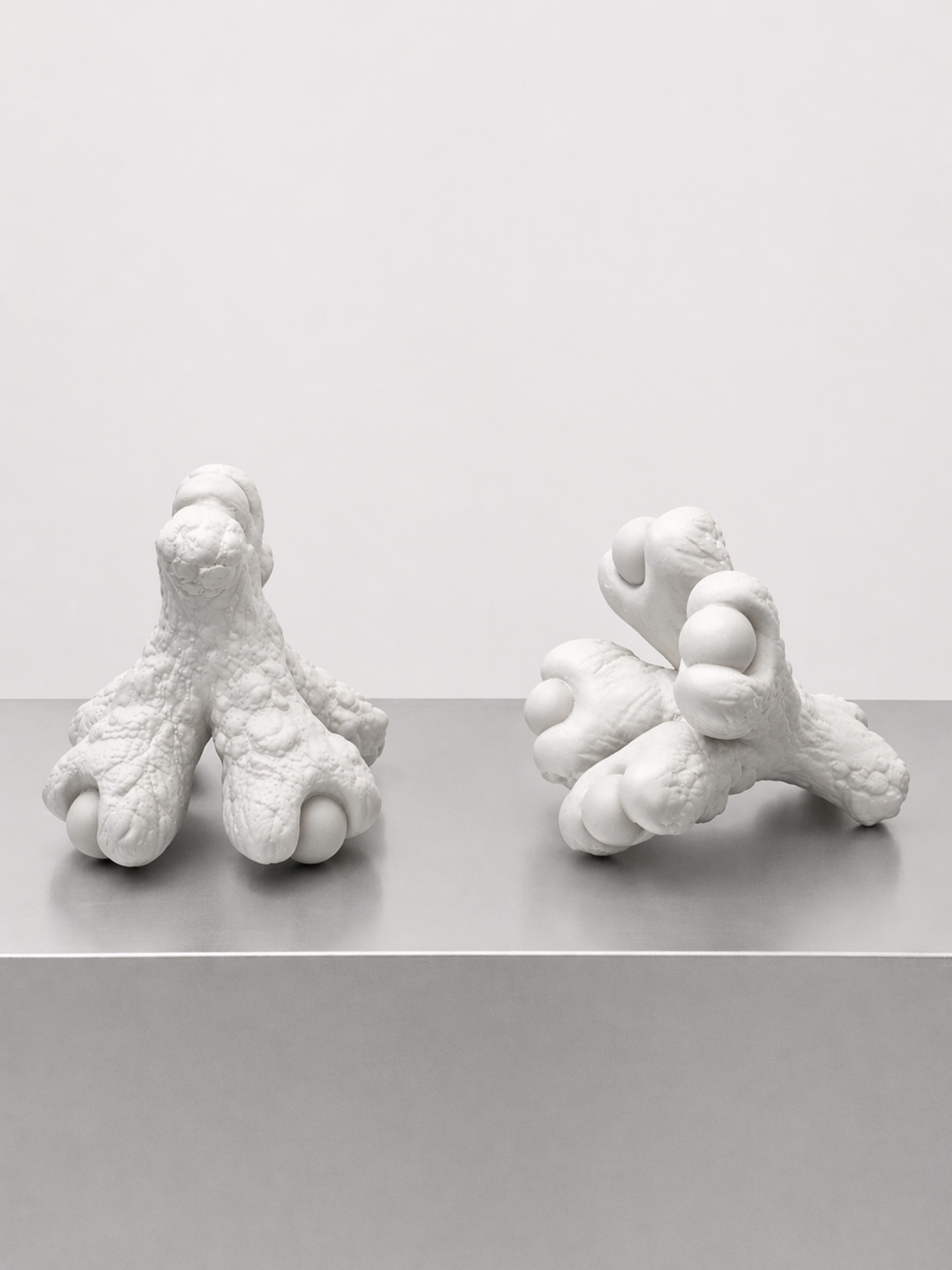 Two white Rebone organizm'os modular parts resting on a metal surface