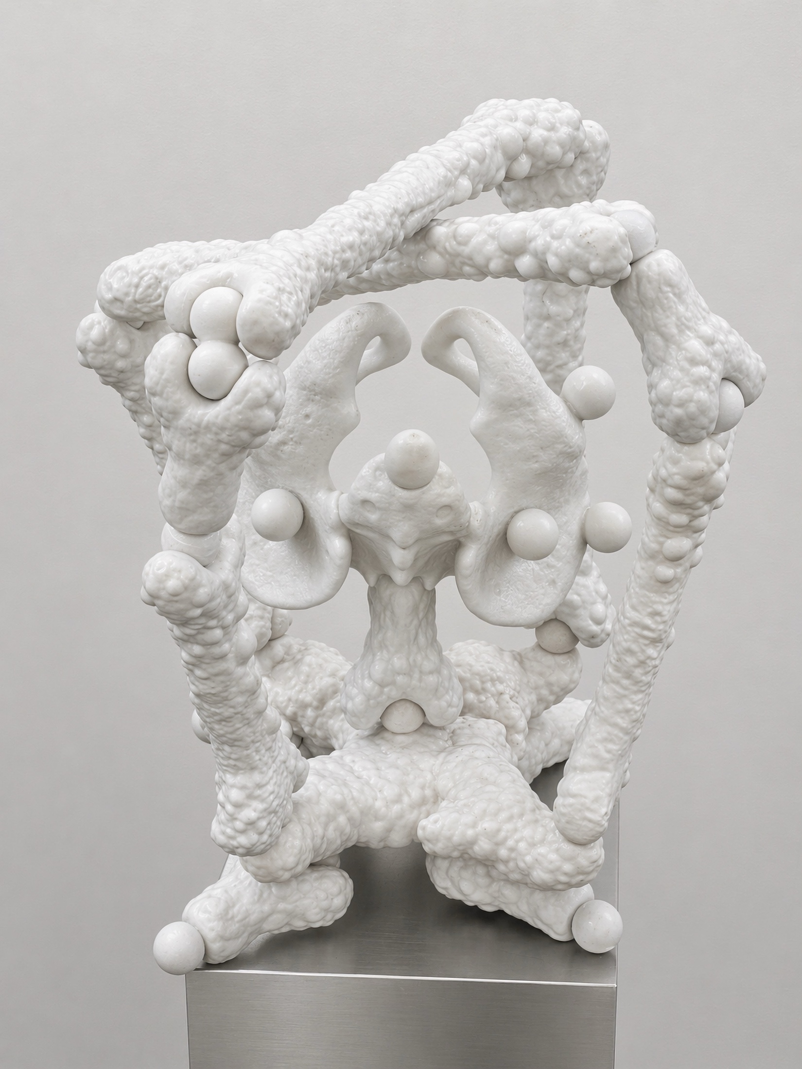 Close view of a white Rebone organizm'os skeletal structure with pelvis-like elements on a metal plinth